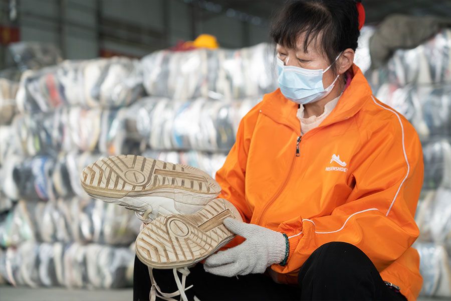 female sorter inspects the soles of a used shoe pair